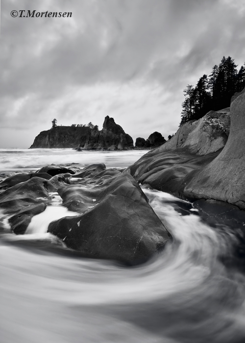 The fluid flow of the ocean swirls around the rocks on Ruby Beach during a morning storm.&nbsp;